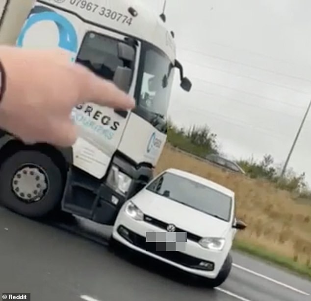 ‘STOP you f***ing idiot!’: Moment truck driver blindly pushes car SIDEWAYS along the M1