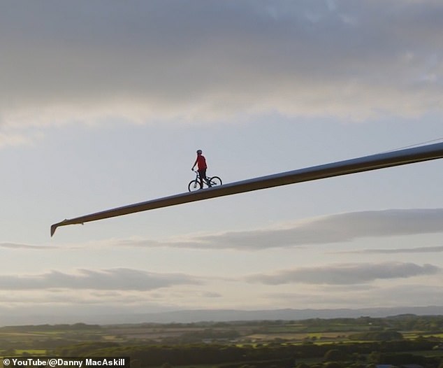Stunt cyclist rides bike along the blade of a 230ft wind turbine