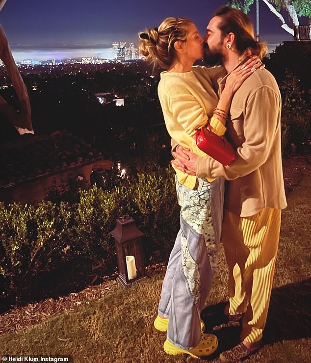 Heidi Klum and Tom Kaulitz kiss while overlooking a city skyline after starring in spooky short