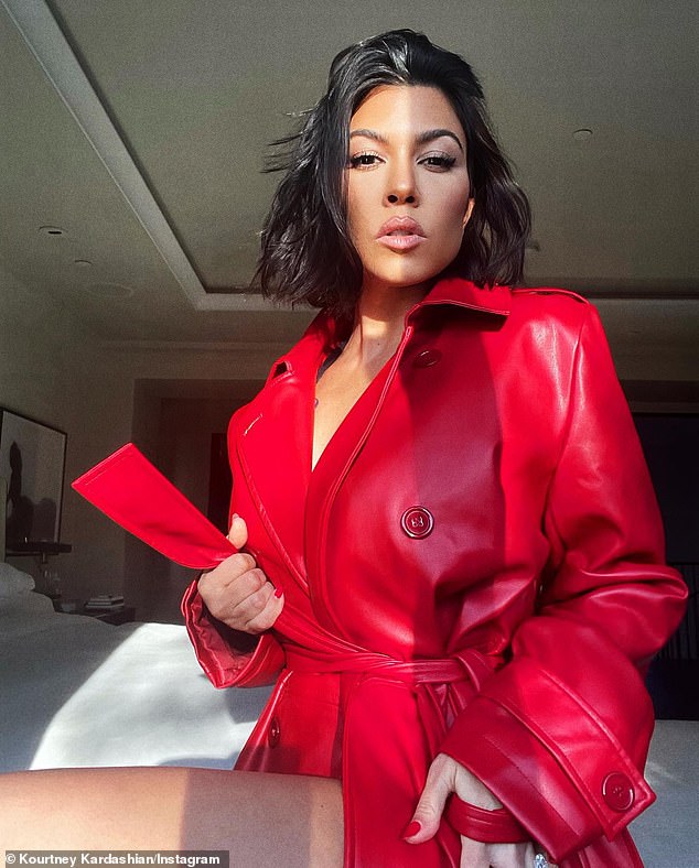 Kourtney Kardashian models a red coat with nothing underneath