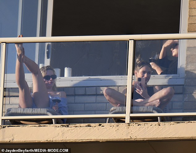 Sisters Madeline and Simone Holtznagel sip wine on the balcony of Justin Hemmes’ Coogee apartment