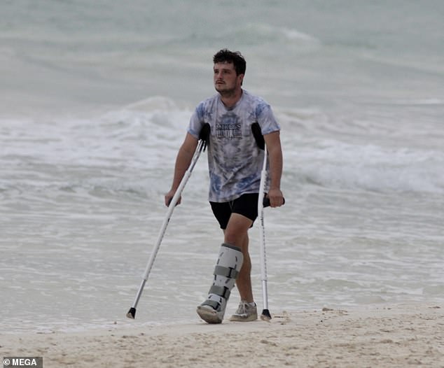 Josh Hutcherson uses crutches to support himself while making his way along a Mexican beach