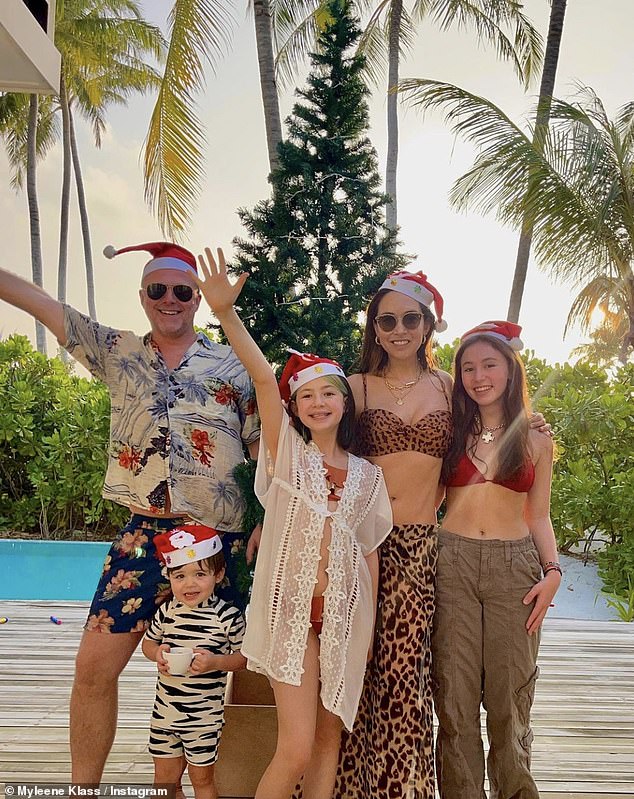 Myleene Klass flashes her abs in a festive family photo as they pose in swimwear and Santa hats