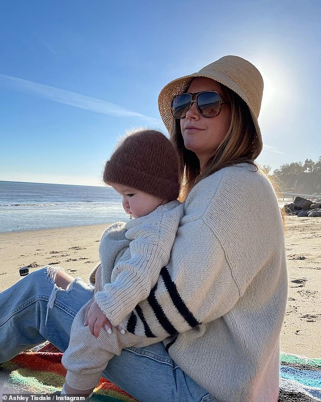 Ashley Tisdale cuddles her daughter Jupiter on the beach as she welcomes the New Year