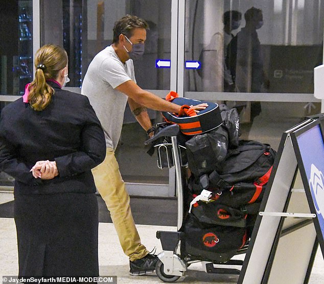 Lachlan Murdoch pushes suitcases through Sydney airport after arriving with wife Sarah and children