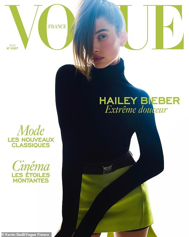 Hailey Bieber poses in a mod black turtleneck and mini skirt for the cover of Vogue France