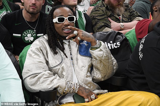 Quavo is blinged out in bracelets and a diamond grill at NBA playoff game in Boston